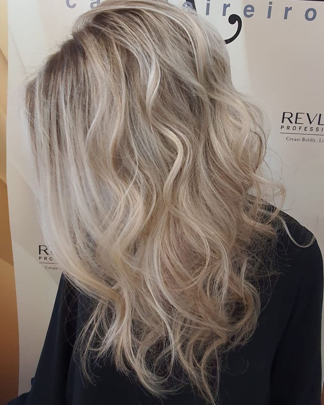 Cabelo louro com ondas, em frente ao painel do salão