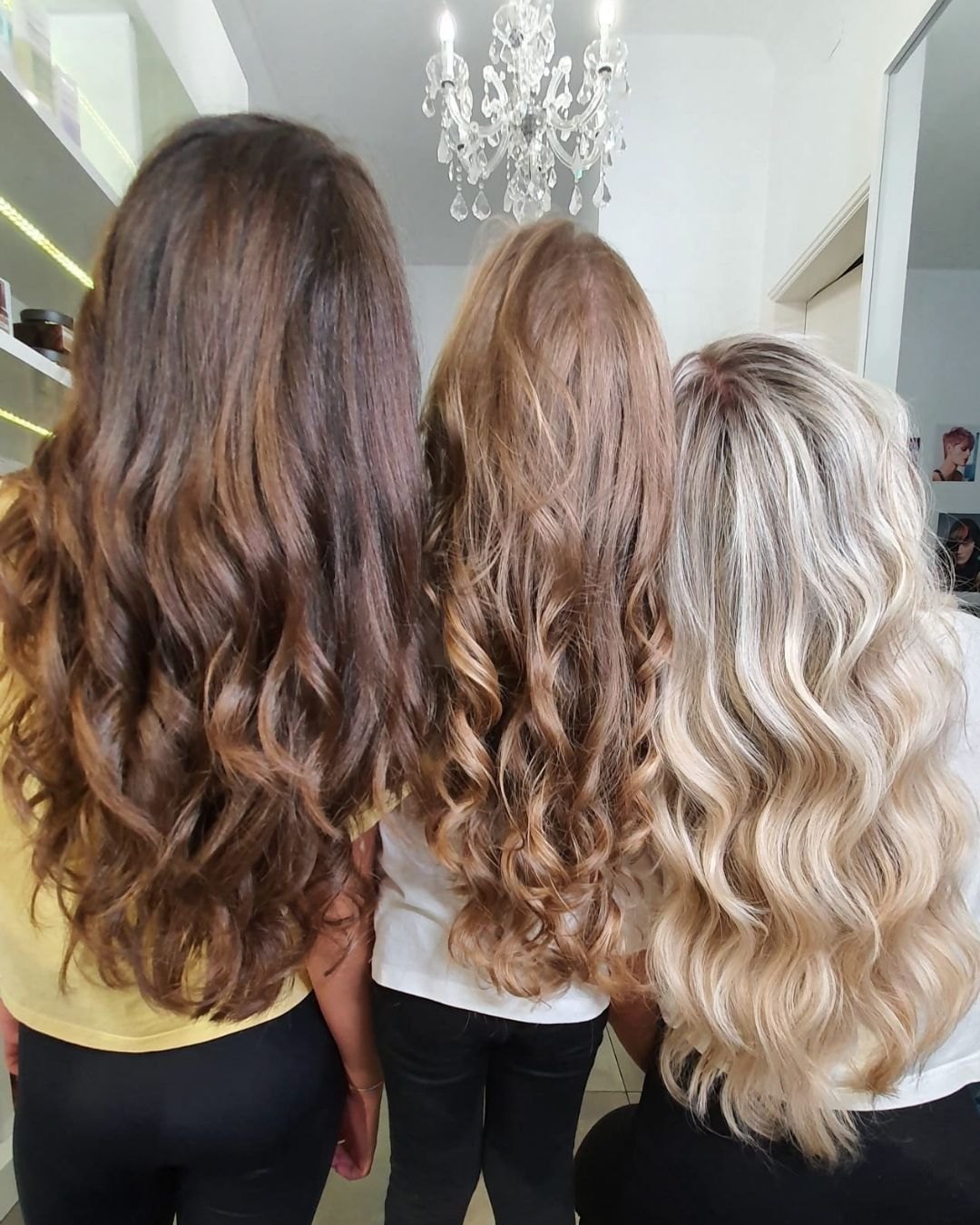 Três clientes de costas, com cabelo castanho, caramelo e louro ondulados